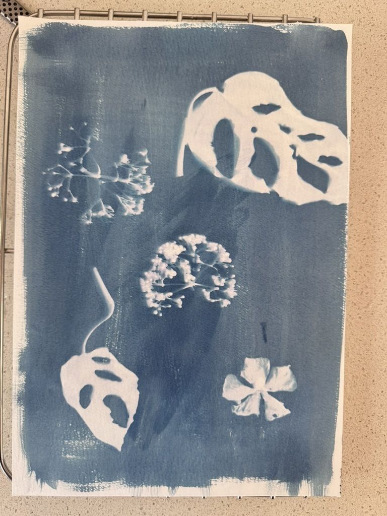 Blue and white artwork of leaves and flowers on a textured surface.