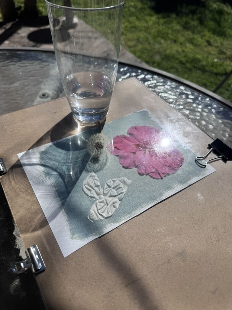 A glass of water and a paper with floral designs on a table.