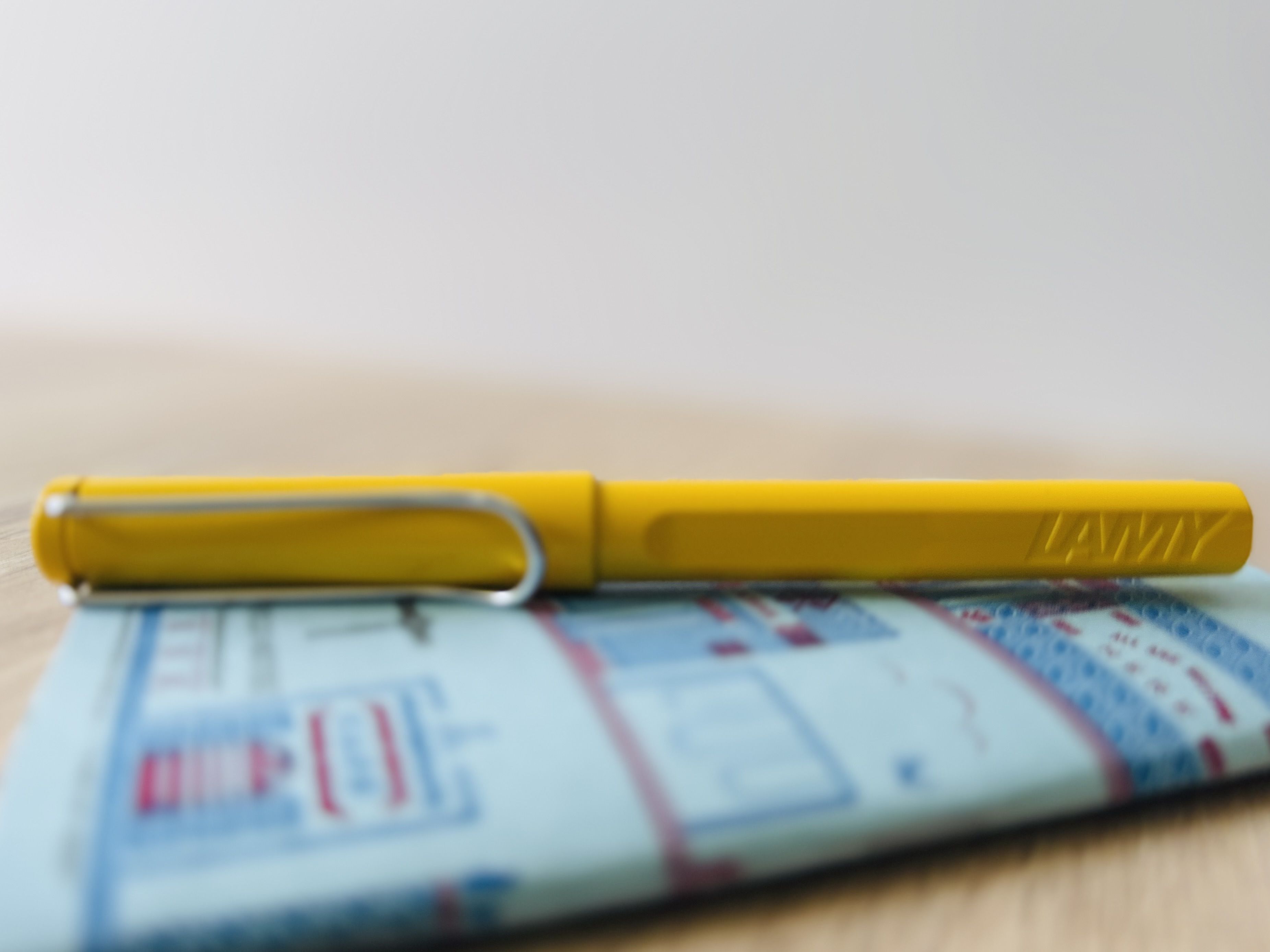 A yellow LAMY pen lying on a blue notebook
