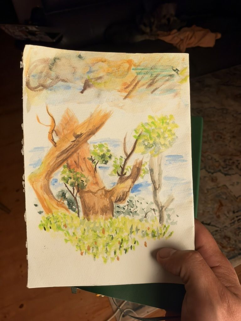 A hand holds a watercolor painting of a tree and foliage.