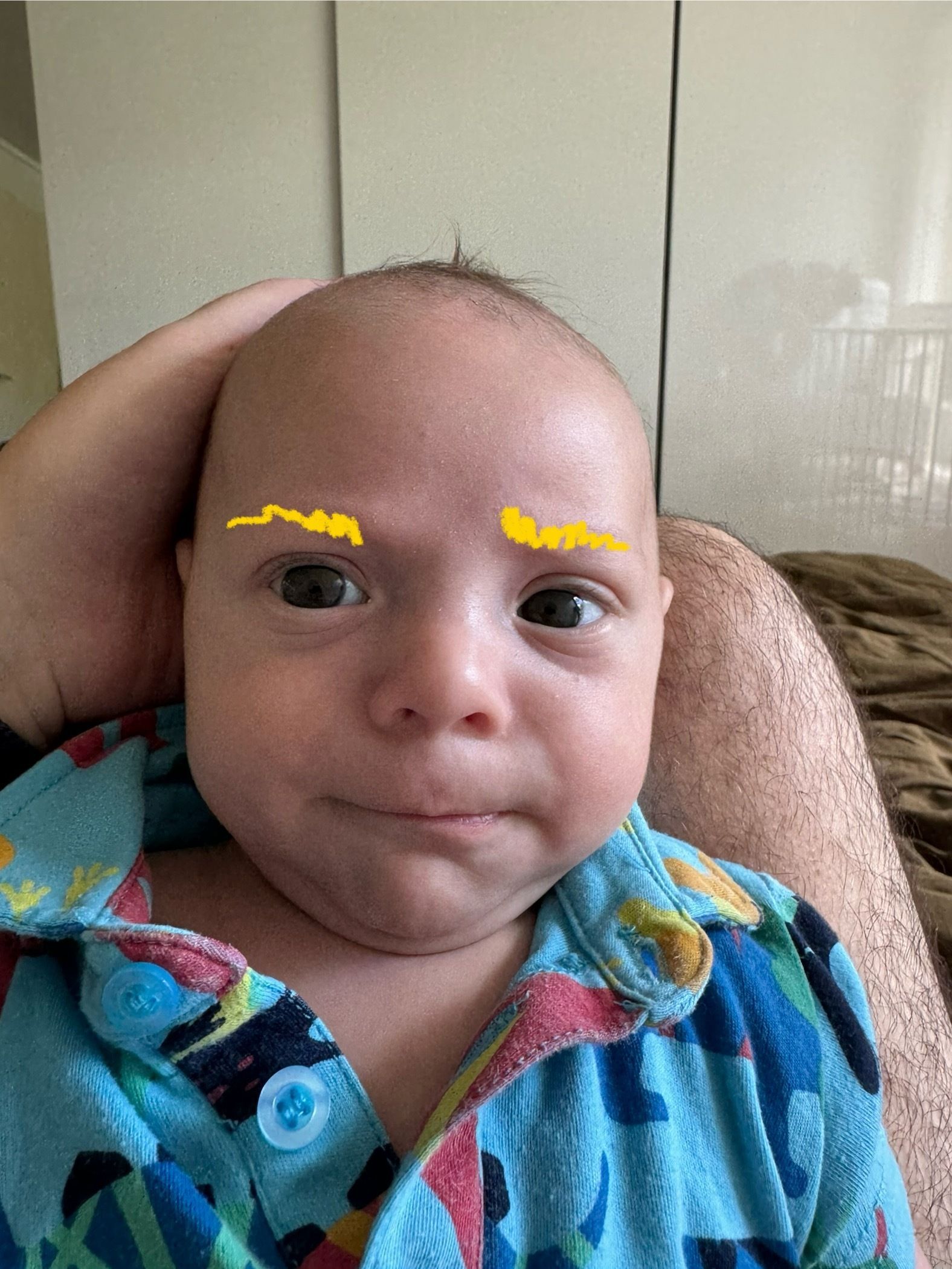 A baby’s face with eyebrows drawn on (digitally)